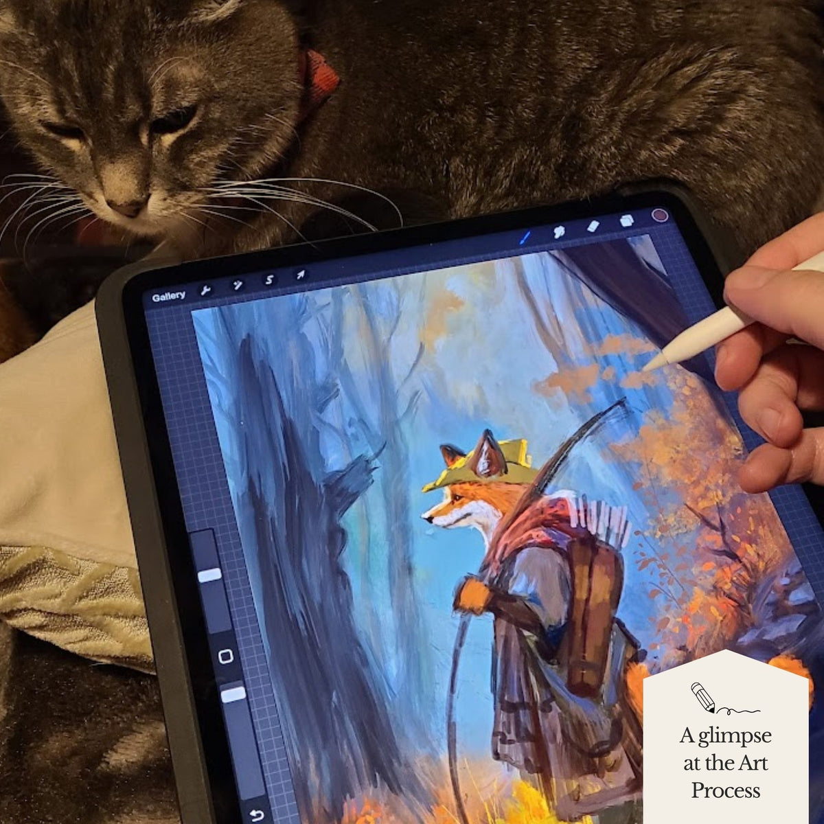 A tablet on a bed with a gray tabby cat resting nearby, showing a digital art illustration in progress. A hand holds a stylus over the screen, which displays a painted fox character in a forest scene.
