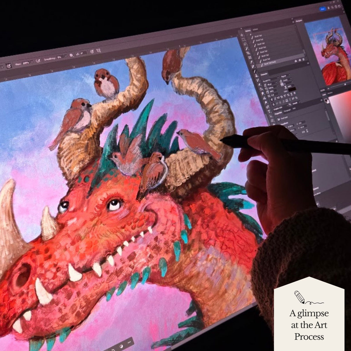 A close-up of a digital illustration in progress on a tablet screen, showing a red dragon with small birds on its horns against a pink sky. A human hand holding a stylus is visible at the lower right, and a badge in the corner reads 'A glimpse at the Art Process'.