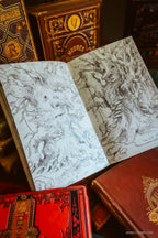 An open sketchbook with detailed black ink drawings of a tree spirit, surrounded by vintage red and gold-bound books.